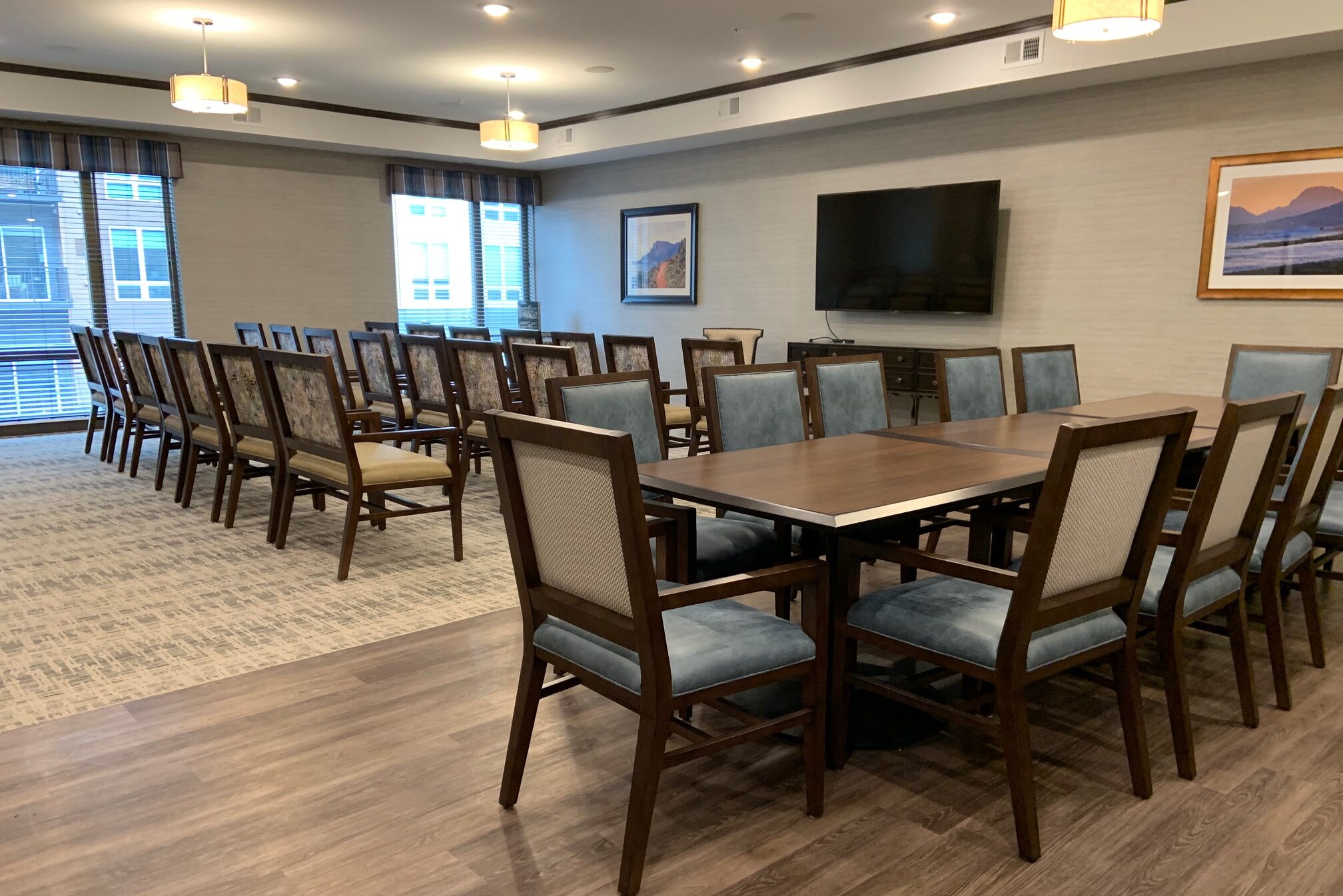 Assisted living community room with tables, chairs and TV empty